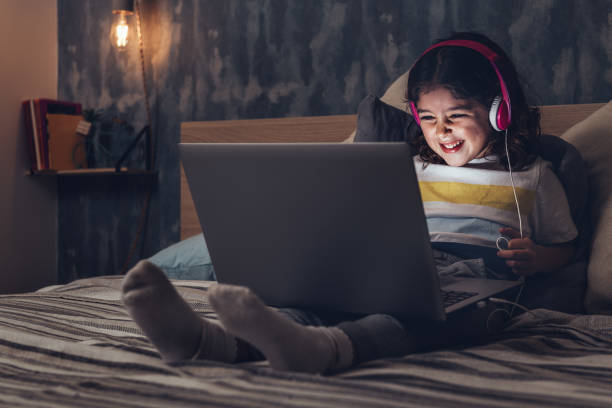 menina sorrindo com um laptop na escuridão - dark little girls child happiness - fotografias e filmes do acervo