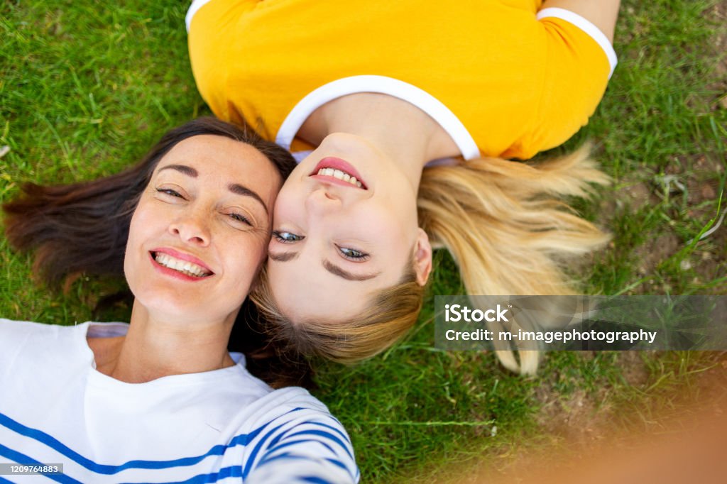 glückliche Mutter und Tochter liegen auf Gras und machen selfie - Lizenzfrei Frauen über 40 Stock-Foto
