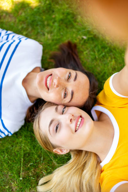 istock happy mother and daughter taking selfie lying on grass outside 1209764884