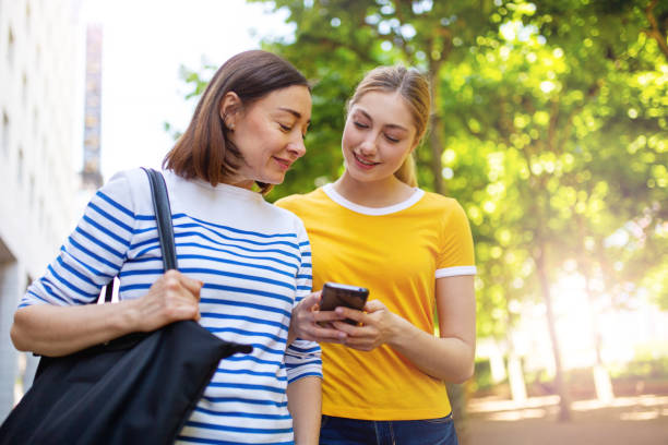 istock mother and daughter standing outside looking mobile phone together 1209764903