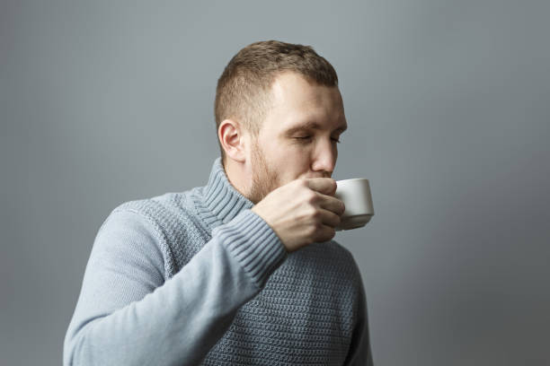 istock Guy in sweater drinking a cup of coffee 1209767671