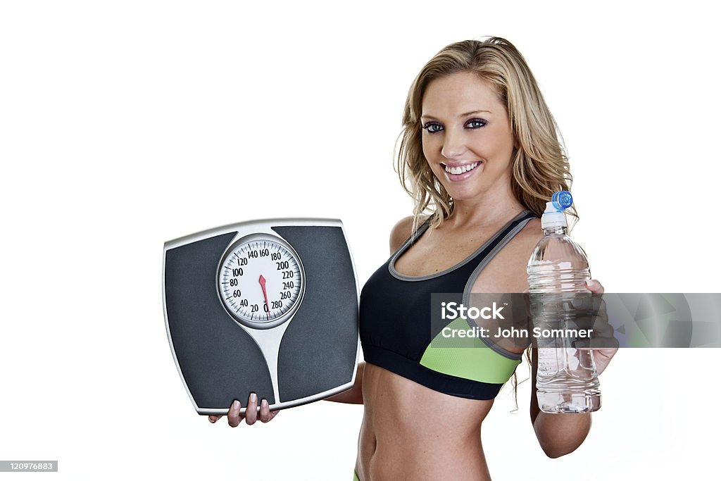 Fitness woman holding scale and water bottle Fitness woman holding a scale and water bottle  20-24 Years Stock Photo