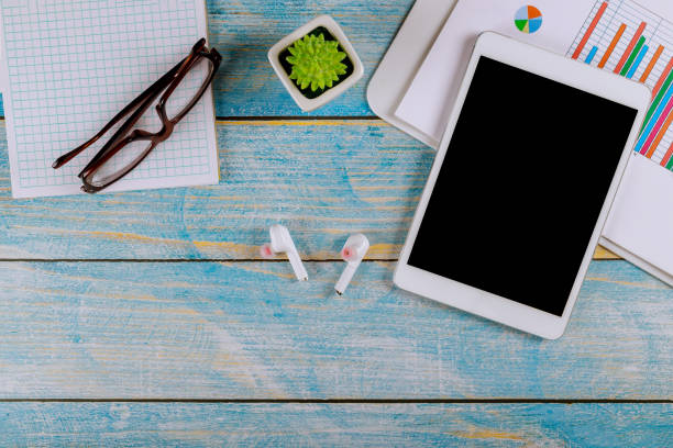 istock Office desk table with digital devices tablet supplies on notepad with wireless headphones glasses 1209774183