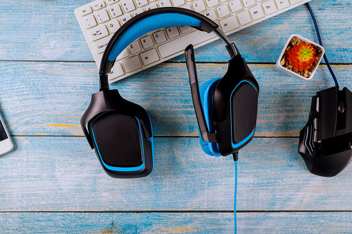 Gamepads headphones and keyboard with mouse on old wood blue table background.