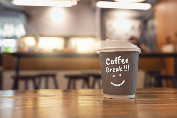 istock Gray paper cup on wooden table in coffee shop. with text 
