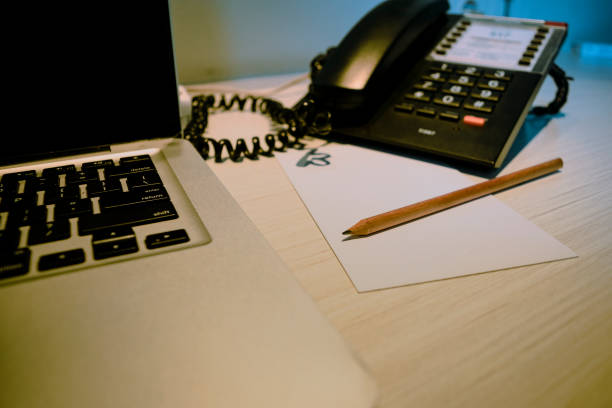 selective focus at pencil on the paper at working table with laptop and desk telephone