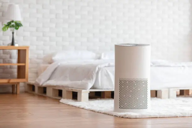 Photo of Air purifier in cozy white bed room for filter and cleaning removing dust PM2.5 HEPA in home,for fresh air and healthy life,Air Pollution Concept
