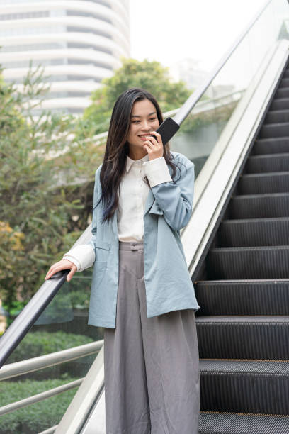 istock A young Asian business woman is using mobile voice messages 1209803175