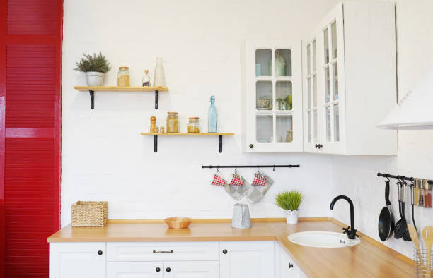 istock Modern new light interior of kitchen with white furniture, white brick wall and different cute jars on the shelves. 1209806859