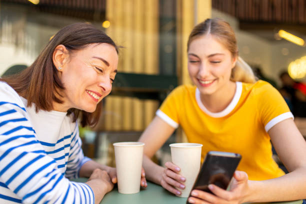 istock mother laughing at daughters mobile phone while sitting at cafe 1209808668