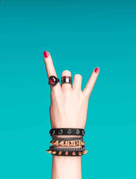 signe de main de roche, geste punk rock féminin avec bracelets de poignet d’or et anneaux de doigt isolés, bannière créatrice de protestation d’art, accessoires de hipster de mode, rendu 3d - bracelet jewelry personal accessory wristband photos et images de collection