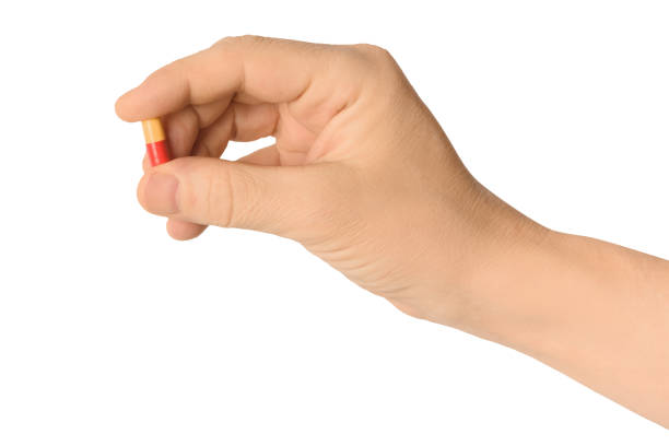 istock Hand holding a pill between thumb and forefinger isolated on white background 1209813380