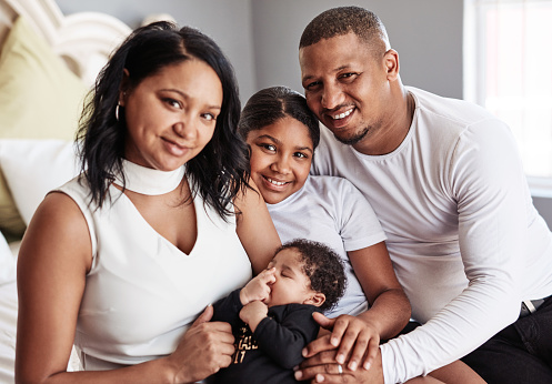 Cropped shot of an adorable young family sitting with their little baby girl at home