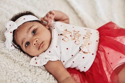 High angle portrait of an adorable baby girl lying down wearing a dress that says \