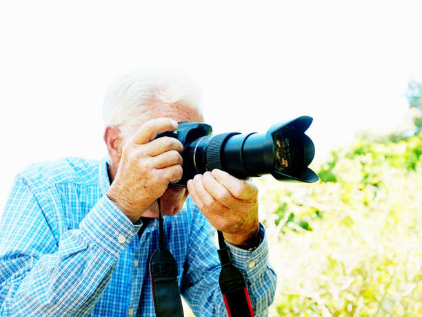 istock Senior man concentrates as he focuses his camera 1209822163