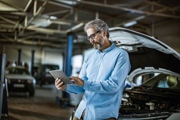 inspector masculino usando tableta digital en taller de reparación de automóviles. - auto repair shop mechanic digital tablet customer fotografías e imágenes de stock