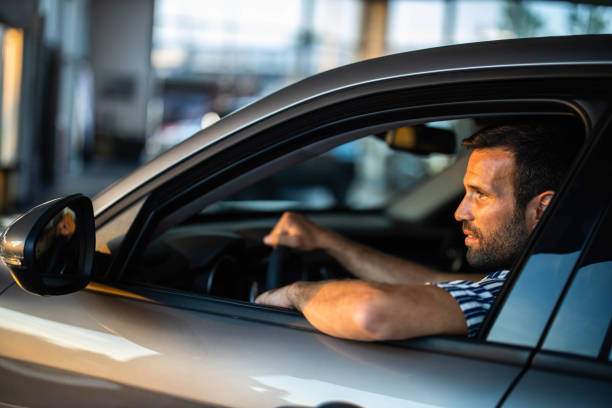 istock Young man testing a car in a showroom. 1209822308