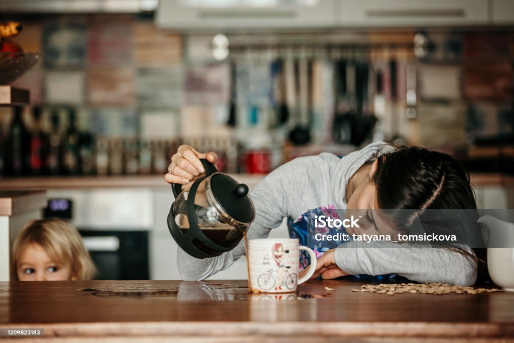 Müde Mutter, versuchen, Kaffee am Morgen zu gießen. Frau liegt nach schlafloser Nacht auf Küchentisch - Lizenzfrei Müde Stock-Foto