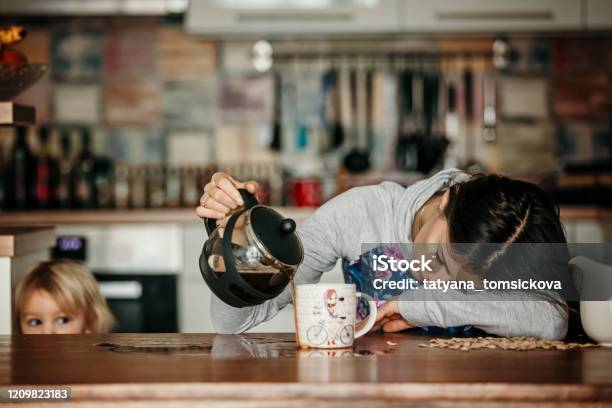 Tired Mother Trying To Pour Coffee In The Morning Woman Lying On Kitchen Table After Sleepless Night Stock Photo - Download Image Now