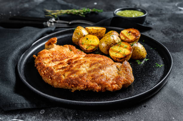 cotoletta di weiner tedesca impanato con patate. sfondo nero. vista dall'alto - weiner schnitzel foto e immagini stock