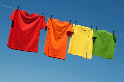 Joyful summer laundry. Colorful t-shirts on a laundry line and blue sky.