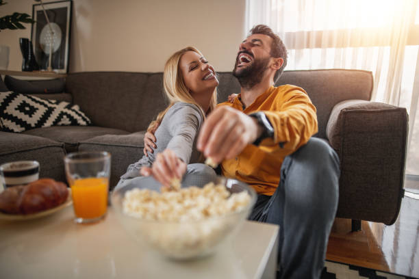 Portrait of happy couple enjoying at home and watching television together stock photo