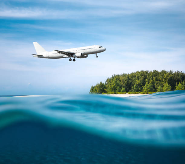 Landing On Tropical Island Commercial airplane flying above tropical island (combined underwater and surface view). planes flying overhead stock pictures, royalty-free photos & images