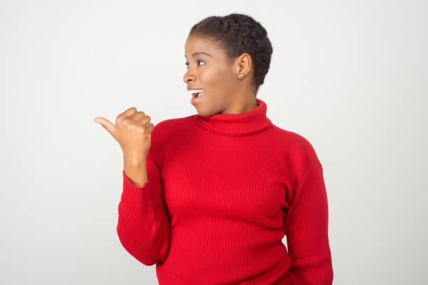 istock Beautiful smiling woman pointing with thumb to left 1209839221