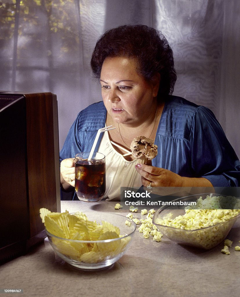 heavy mujer viendo televisión y comiendo comida de basura - Foto de stock de Comer demasiado libre de derechos