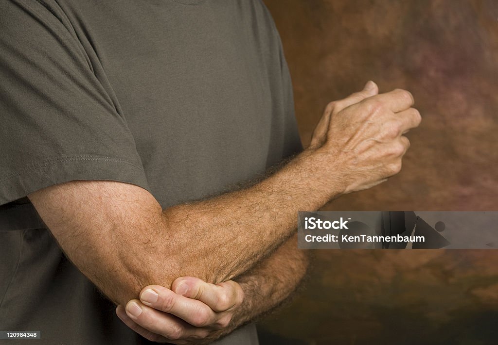 man massaging elbow in pain  Adult Stock Photo