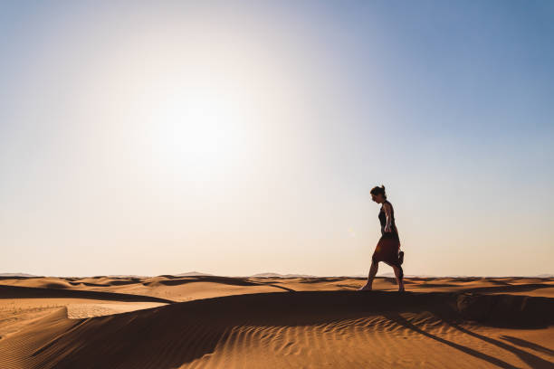 istock Woman walks along the dune's peak 1209846431