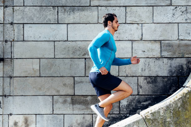 istock Side view of young man jogging on steps by wall 1209846998