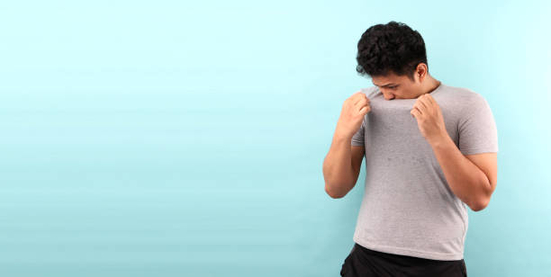 Asia Man sweating excessively smelling bad isolated on bluebackground in studio With copy space. Asia Man sweating excessively smelling bad isolated on bluebackground in studio With copy space. body odor stock pictures, royalty-free photos & images