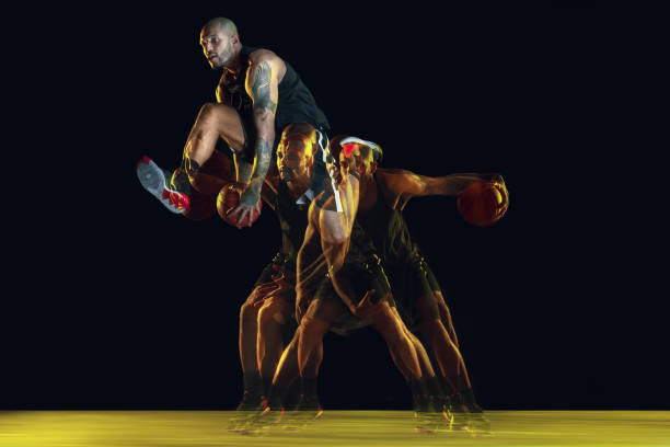 istock Young basketball player training on dark studio background in neon, strobe light 1209850682
