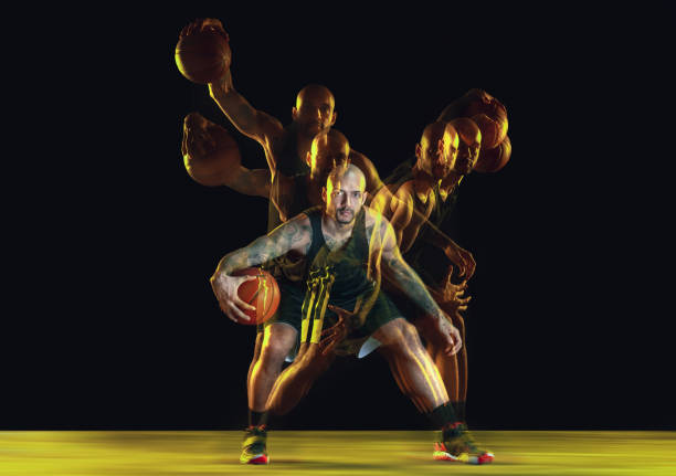 istock Young basketball player training on dark studio background in neon, strobe light 1209850688