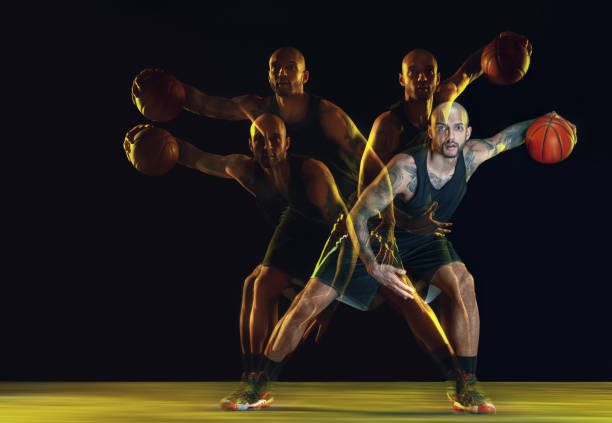 istock Young basketball player training on dark studio background in neon, strobe light 1209850690