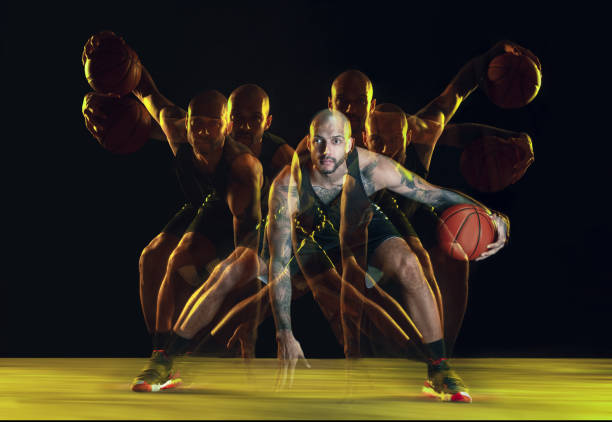 istock Young basketball player training on dark studio background in neon, strobe light 1209850694