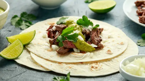 Carne Asada Tacos with grilled steak, green sauce and onion. Mexican food.