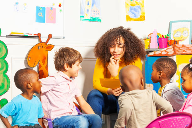 istock Teacher in kindergarten  reading a book to kids 1209856770