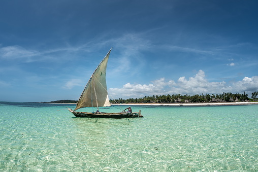 tropical landscape with traditional wooden sail boat on the crystal clear water as in Maldives or Carribean islands