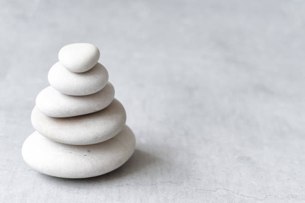 istock Stack of white pebbles on a neutral light grey background as balance and wellness concept 1209856936