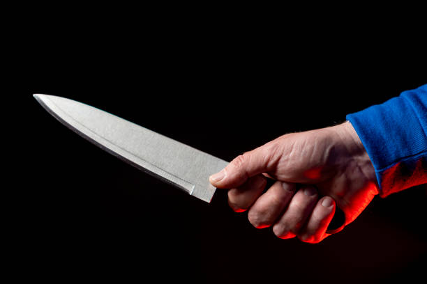 istock Kitchen knife in a man's hand close-up on a black background 1209857391