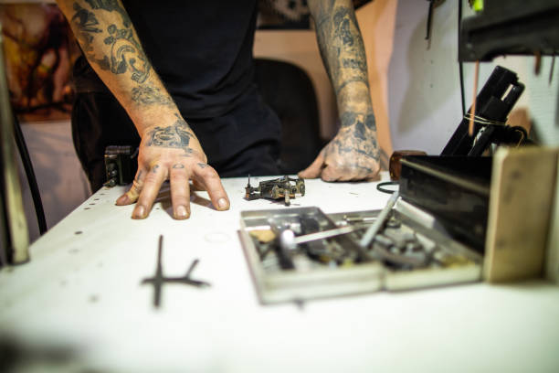istock Tattoo of tattoo machine on hand and model on workbench 1209861319
