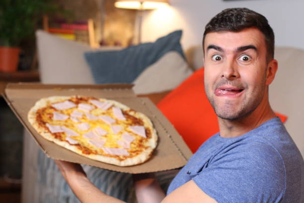istock Enthusiastic man enjoying pizza at home 1209862274
