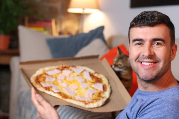 istock Enthusiastic man enjoying pizza at home 1209862275