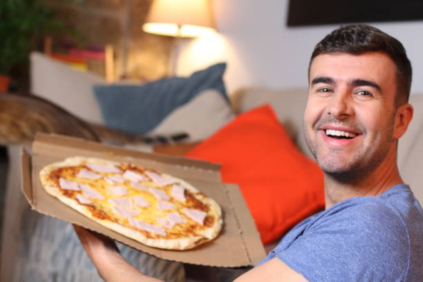 istock Cheerful young man holding a pizza 1209862295