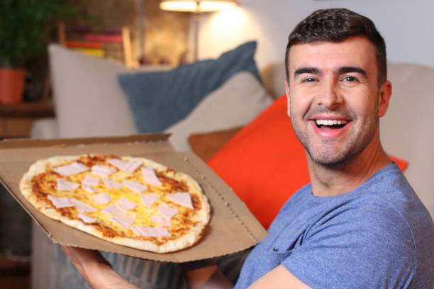 istock Enthusiastic man enjoying pizza at home 1209862344
