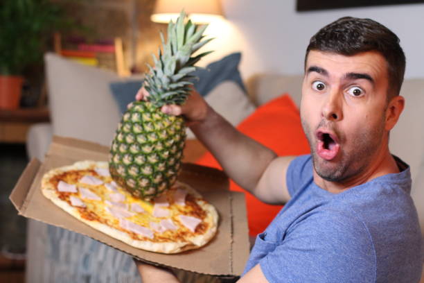 istock Man mixing a whole pineapple with pizza 1209862348