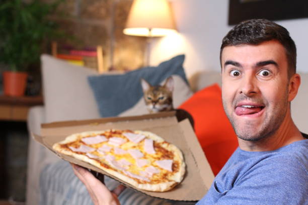 istock Enthusiastic man enjoying pizza at home 1209862376