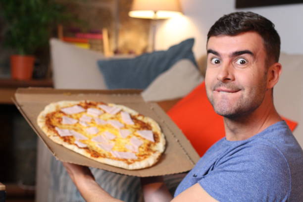 istock Enthusiastic man enjoying pizza at home 1209862387
